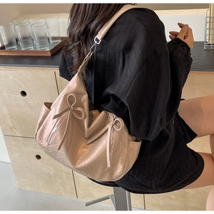 Detail view of pink bucket bag with pleated texture, bow ribbons and dual metal zippers