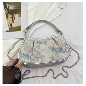 Detail of floral jacquard embroidery on semi-moon bag with metallic silver accents