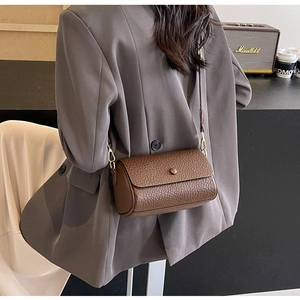 Detail view of a vintage dark brown cylindrical crossbody bag on a model shoulder