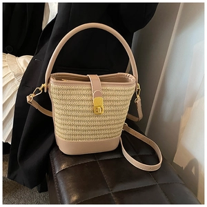 Detail of woven straw bucket bag featuring pink leather trim and gold metal clasp