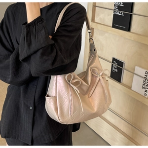 Side view of pink pearlescent tote bag with bow detail and textured faux leather finish
