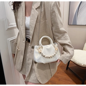 Sac nuage plissé blanc avec poignée en perles de marbre et chaîne porté par un mannequin