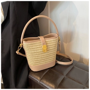 Detail of woven straw bucket bag with smooth leather trim and golden twist lock closure