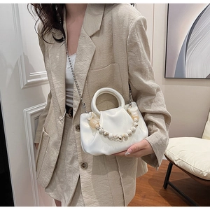 Détail d'un sac nuage plissé blanc avec une poignée élégante en perles marbrées
