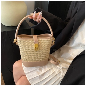 Detail of hand-woven straw bucket bag with faux leather strap and golden metal clasp