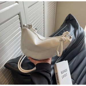 Close-up of white leather hobo bag with unique knotted handle and zip closure detail