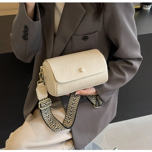 Close-up of off-white cylindrical bag featuring textured leather and a geometric woven strap