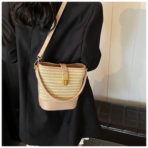Detail of hand-woven straw bucket bag with pink leather trim and gold twist lock