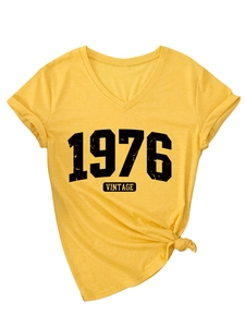 Close-up of yellow V-neck T-shirt showing 1976 Vintage print and knotted hem detail
