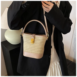 Detail of woven straw bucket bag featuring a gold CD metal clasp and leather trim