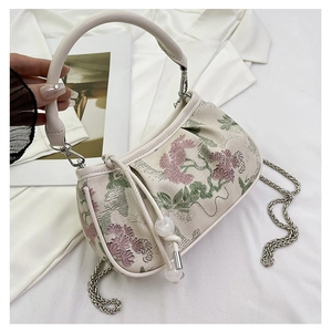 Close-up of vintage floral embroidery and beaded drawstring detail on a cream bag