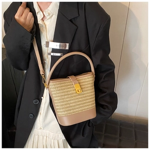 Detail of woven straw bucket bag with gold twist lock and adjustable shoulder strap