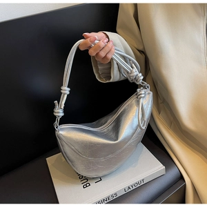 Detail of silver half-moon handbag with metallic pleated texture and knotted strap design