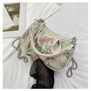 Detail of floral embroidery on small square bag with silver chain and white leather trim