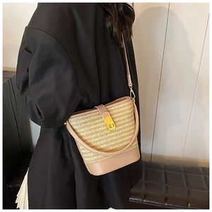 Detail showing the straw bucket bag texture and leather strap worn by a model