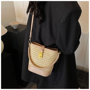 Detailed view of woven straw bucket bag with khaki leather trim and gold metal lock