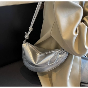 Silver crescent dumpling bag with pleated metallic finish worn by model over shoulder