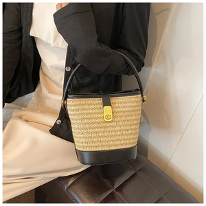 Detail of woven straw bucket bag with black leather base and gold CD buckle