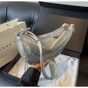 Detail of silver metallic crescent bag with wrinkled texture and knot shoulder strap