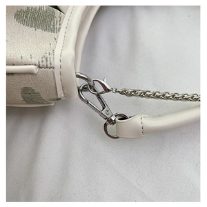 Detailed close-up of canvas embroidery bag with green heart pattern and silver metal chain