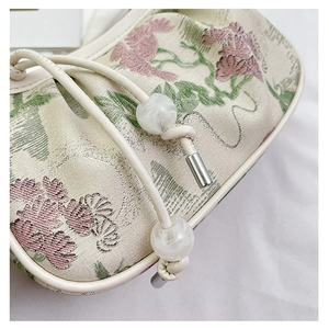 Detail of floral jacquard fabric with leather drawstring and marble bead ornaments