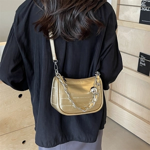 Sac bandoulière doré à motif crocodile et chaîne argentée porté par un modèle