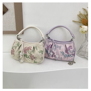 Detailed close-up of exquisite floral embroidery on small vintage crescent handbags