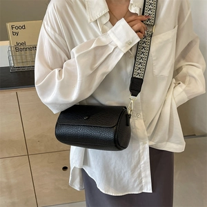 Minimalist black cylinder shoulder bag with a vintage geometric pattern wide strap