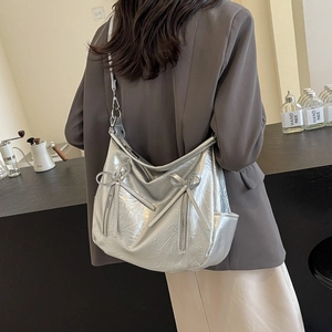 Metallic silver bucket bag with bow details and lychee texture shown in a cross-body style