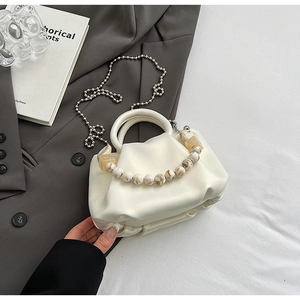 Détail du sac nuage plissé blanc avec chaîne en perles marbrées sur un blazer