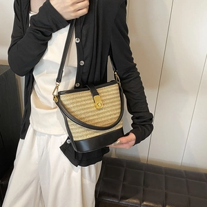 Woven straw bucket bag with black leather trim and gold metal clasp for summer