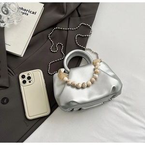Détail du sac nuage plissé argenté avec poignée en perles ambre et chaîne métal