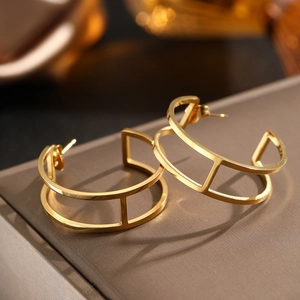 Detailansicht der goldenen geometrischen Ohrringe mit doppellagigem Hohlmuster auf Luxus-Hintergrund