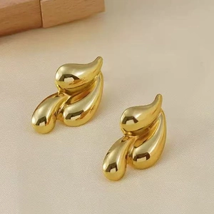 Macro shot of gold teardrop stud earrings with a polished finish on textured fabric