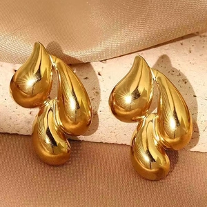 Detailed shot of gold triple teardrop earrings on a stone base with silk fabric decor