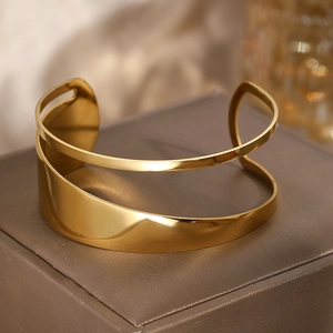 Macro shot of gold wide hollow cuff bracelet showing smooth waves and polished finish