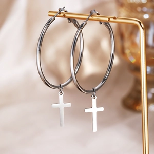 Pair of silver stainless steel hoop earrings with polished cross pendants on a gold display
