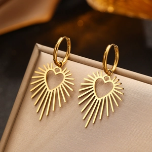 Golden stainless steel heart earrings with radiating sunburst design on a jewelry box
