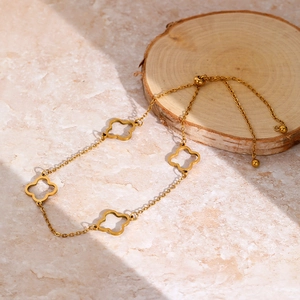 Elegant 18K gold-plated stainless steel clover anklet on a minimalist wooden display