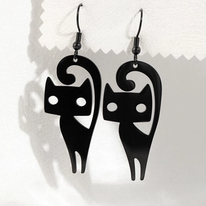 Detailed macro view of black minimalist cat pendant earrings on a textured display card