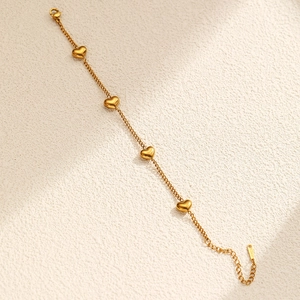 Detailed macro view of 18K gold plated stainless steel heart charm bracelet and lobster clasp