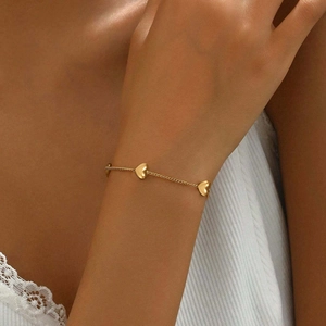 Close-up of a gold stainless steel chain bracelet with three 3D heart pendants