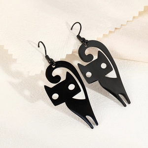 Minimalist black stainless steel hollow cat dangle earrings on textured beige background