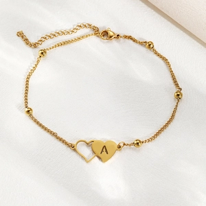 Detail of gold stainless steel anklet with overlapping heart pendants and letter A engraving