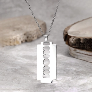 Vintage stainless steel razor blade pendant necklace with silver O-chain on natural wood background