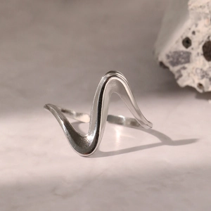 Vue macro d'une bague argentée ondulée minimaliste avec surface polie sur fond de pierre