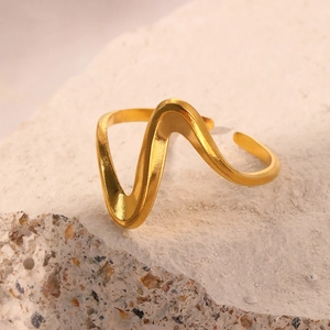 Macro d'une bague dorée ondulée irrégulière posée sur une surface de roche blanche