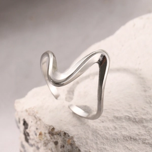 Macro d'une bague vague argentée aux lignes irrégulières sur fond de pierre blanche