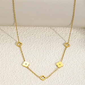 Detailed shot of golden stainless steel necklace with clover charms on textured background