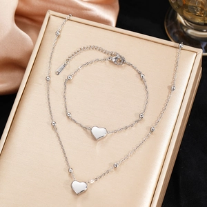 Polished stainless steel heart pendant necklace and beaded bracelet set on display